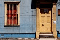 Un antiguo edificio con escaleras de mármol y camino de cuadros afuera, rejas en la ventana, Valparaíso.