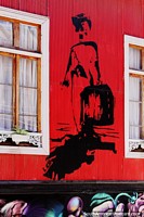 Hombre con una maleta, una imagen negra pintada en un edificio de hierro corrugado rojo en Valparaíso.