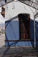 Versão maior do Sombras e luz ao lado de um edifício com persianas de madeira em Antofagasta.
