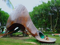 Child slides down the huge dinosaur playground in Parque Santander, Leticia. Colombia, South America.