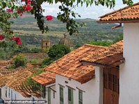 Red flowers, red roofs, cathedral in distance, Barichara. Colombia, South America.
