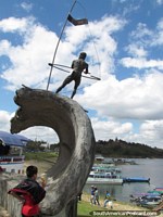 O rapaz de surfe a vela em um monumento de onda perto da lagoa em Guatape. Colômbia, América do Sul.