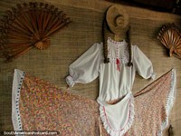 Traditional clothes and hand-held fans hang on the wall at a restaurant in Armenia. Colombia, South America.