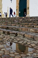 Cobblestone stairs lead up to the church door in Villa de Leyva, reflection in the water. Colombia, South America.