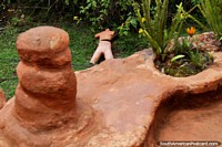Ceramic mannequin lying on the lawn, view from a  patio at the Terracotta House in Villa de Leyva. Colombia, South America.