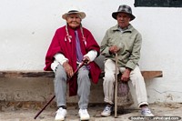 Colombia Photo - Woman with pink shawl, white hat and pigtails sitting with her husband, elder locals of Villa de Leyva.