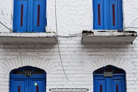 Symmetrical blue doors, above and below, a white wall, the streets of Zipaquira. Colombia, South America.