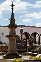 Small park around a fountain with distant arches, a nice day in Guatavita. Colombia, South America.