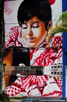 Chica en ropa roja brillante toca la guitarra, impresionante arte callejero en Ibague, la capital de la música. Colombia, Sudamerica.