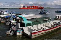 Big red cargo ship and tourist boats around the port and wharf in Buenaventura. Colombia, South America.