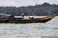 Versión más grande de Pescador arroja un pez en un cubo frente a la costa de Buenaventura.
