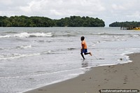 Un chico local de la playa de Juanchaco corre hacia el mar, en la costa del Pacífico al norte de Buenaventura. Colombia, Sudamerica.