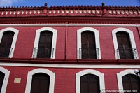 Versão maior do Abóbada de claustro histórica do Colégio Acadêmico em Buga, grande edifïcio vermelho com portas de madeira e balcões de ferro.