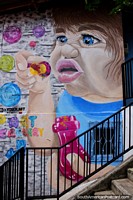 Child blows colored bubbles, art in the streets of Comuna 13 in Medellin.
