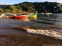 Los barcos rojos, verdes y amarillos brillan en el sol de la tarde en la bahía de Taganga. Colombia, Sudamerica.