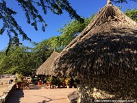 Cabanas cobertas com palha (restaurantes) com árvores e sombra no litoral em Taganga. Colômbia, América do Sul.