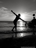 Silhouettes of boys playing soccer at the beach in Taganga at sunset, black and white. Colombia, South America.