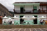 Belo edifício com um café com mesas ao ar livre ao lado da igreja em Jardin. Colômbia, América do Sul.