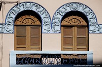 Blue decorated arches above a pair of brown wooden doors and a balcony, architecture in Pereira. Colombia, South America.