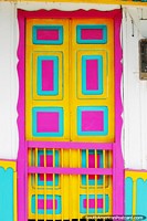 Bright door in pink, yellow and teal in the colorful streets of Salento. Colombia, South America.