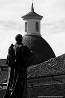 Sacerdote olha através dos telhados para uma cúpula distante em Popayan. Colômbia, América do Sul.