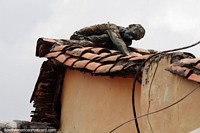 Não é um cadáver apodrecido, isso é arte, uma figura de bronze em um telhado de telhas vermelhas em La Candelaria, Bogotá. Colômbia, América do Sul.