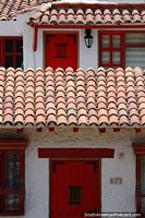 Bela fachada de uma casa colonial com telhado de telhas vermelhas e portas vermelhas em Pueblito Boyacense, Duitama. Colômbia, América do Sul.