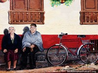 Elder man and woman sit outside a house, a bicycle beside, mural on a house side in Sogamoso.