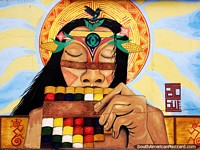 Hombre indígena soplando coloridos tubos de madera, mural callejero en Sogamoso. Colombia, Sudamerica.