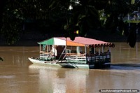 Platform boats cross the Sinu River regularly taking people back and forth in Monteria. Colombia, South America.