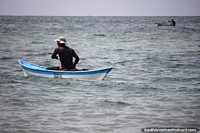 Um homem sozinho em uma canoa no mar, mas ele tem um companheiro distante, local da Ilha de Tintipan. Colômbia, América do Sul.
