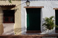 An elegant and tidy house facade near the river in Mompos with a green plant and lamp. Colombia, South America.