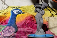 Fuente con un colorido mural pintado detrás con un gran pavo real en Minca. Colombia, Sudamerica.