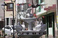 Silver fountain and pink flowers, a pigeon flies over, neighborhood in Pamplona. Colombia, South America.