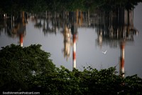 Chaminés altas da usina de petróleo Barrancabermeja refletindo no rio Magdalena. Colômbia, América do Sul.