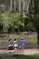 People beside the river with bearded trees above at El Gallineral Natural Park in San Gil.