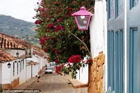 Cobblestone street in Barichara with pink lantern, pink flowers and blue door.