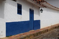 Paredes encaladas de una casa en Barichara, una puerta y ventana azules y una linterna. Colombia, Sudamerica.
