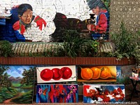 Paintings for sale in the street with a mural of indigenous people above in Pasto. Colombia, South America.