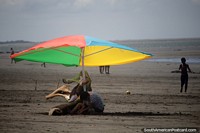 Colorful umbrella really stands out with a background of sand far into the distance in Tumaco. Colombia, South America.