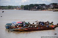 Boats in a group and wooden houses on the banks of the Atrato River in Quibdo.
