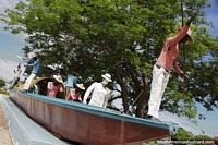 Fishermen in action, monument with boat under a big tree in Santa Marta.