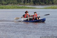 A pair paddle a double kayak on the Amazon River in Mocagua, Leticia. Colombia, South America.