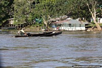 Homem em uma canoa fluvial dirige-se para a costa na Amazônia em torno de Leticia.
