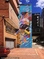 Mujer con flores, mariposas y un jaguar, enorme mural callejero en un edificio de Bogotá.