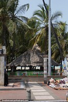 Restaurante de praia com telhado de palha sob palmeiras em Riohacha.