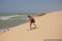 De p ou sentado, pratique sandboard nas dunas de Taroa, no norte de Guajira.