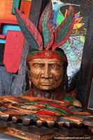 Larger version of Arts and crafts in Mindo, an indigenous man with feathers sculpted from wood.