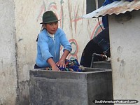 Una niña ayuda a la madre a lavar la ropa en una tina exterior en las tierras altas. Ecuador, Sudamerica.
