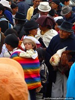 Os homens e a mulher ambos usam tecidos tradicionais em mercados de Otavalo. Equador, América do Sul.